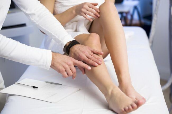 the doctor examines the leg with reticular varicose veins